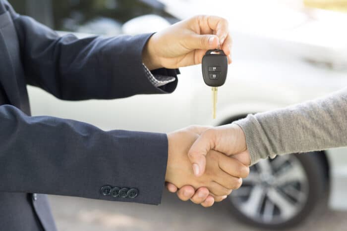 vendeur présente la clé de la voiture à son client